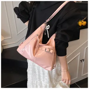 Detail of pink patent leather shoulder bag with zipper decoration and pearl charm accessory