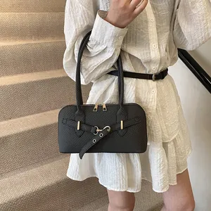 Chic black textured pillow shoulder bag with gold hardware shown on a female model