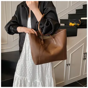 Dettaglio della grande borsa tote marrone in pelle martellata indossata sottospalla