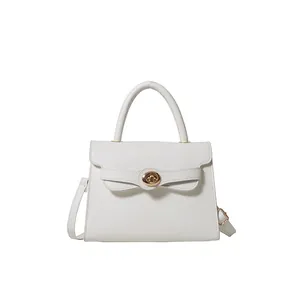 Elegant white structured trapezoid handbag with gold rotating clasp and top handle