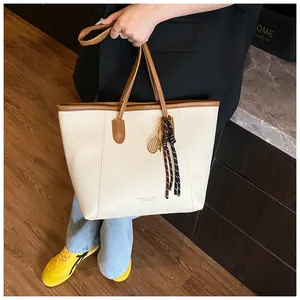 Detail of cream white tote bag with lychee texture, brown straps and tennis racket charm