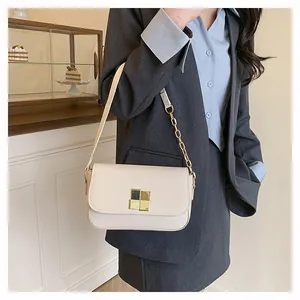 Detail of a chic cream flap bag with gold geometric lock and chain strap on a model
