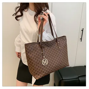 Détail du sac cabas marron avec monogramme, pendentif M doré et rivets métalliques