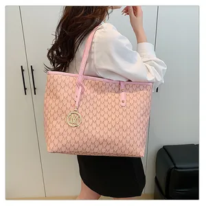 Sac cabas rose à imprimé M et breloque dorée porté à l'épaule par le mannequin