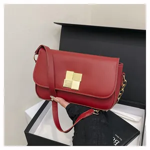 Detail of burgundy leather handbag with gold square clasp inside a black premium gift box