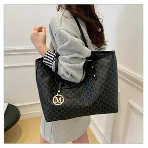 Détail du sac cabas noir avec motif M et breloque métallique dorée élégante
