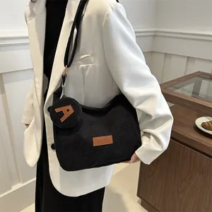 Black corduroy tote bag with small coin purse shown on shoulder in a modern setting