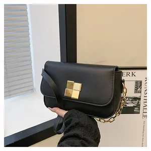 Detail of elegant black leather handbag with square gold lock and chain strap