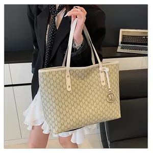 Détail du motif monogramme et du charm M doré sur le grand sac cabas beige chic