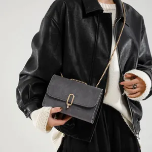 Chic grey frosted crossbody bag with gold U-buckle and metal chain strap on model