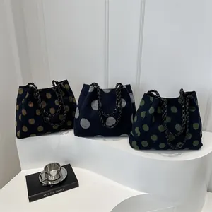 Polka dot woven tote bags in three colors with metallic chain straps on a white display