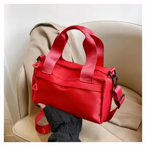 Detalle del bolso bandolera de nailon rojo con acabado satinado y correa ajustable