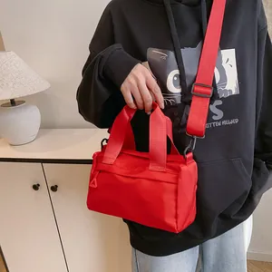 Bolso tote minimalista de nailon rojo con correa ancha para el hombro en una modelo