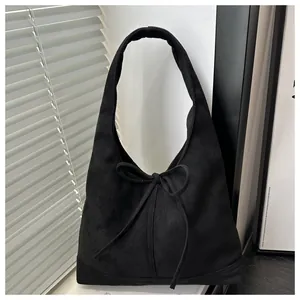 Close-up of black suede hobo bag with stylish bow knot and textured wide shoulder strap