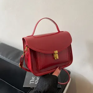 Sac messager vintage rouge en cuir souple avec fermoir doré pour femme, porté épaule ou croisé
