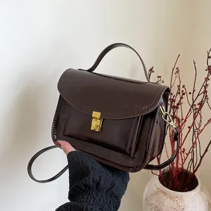 Sac bandoulière rétro marron foncé avec fermoir doré et poignée sur fond minimaliste