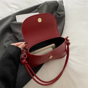 Deep red half-moon hobo bag in matte leather featuring unique twisted knot shoulder strap