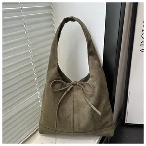 Detail of the soft olive green suede tote bag featuring a decorative bow knot detail