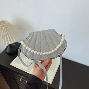 Silver glitter shell handbag with large pearl chain handle on a stylish desk background