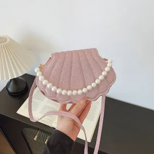 Pink shell-shaped crossbody bag with pearl handle and subtle shimmering felt texture
