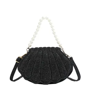 Sparkling black shell bag with white pearl handle and golden metallic hardware