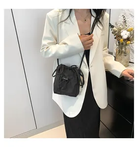 Borsa a tracolla minimalista in nylon nero con coulisse indossata da una modella