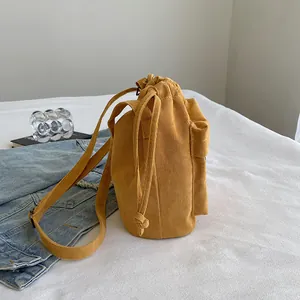 Sac seau en velours côtelé jaune avec cordon de serrage et bandoulière fine sous lumière douce
