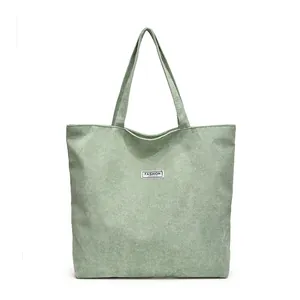 Dettaglio della borsa tote in velluto a coste verde chiaro con trama e patch logo