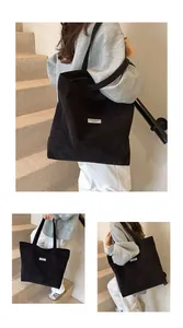 Dettaglio borsa shopper in velluto a coste nero con trama rigata e etichetta bianca