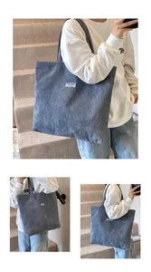 Dettaglio della borsa tote in velluto a coste grigio-blu con trama e etichetta Fashion