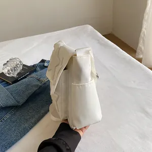 Minimalist white canvas messenger bag with plush star patch on casual bedding background