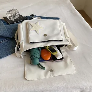 White canvas messenger bag with plush star patch and spacious interior storage