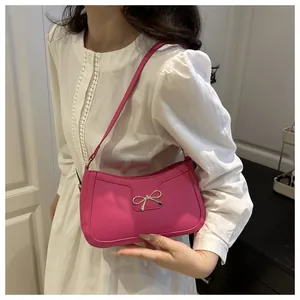 Gros plan du sac à bandoulière rose vif avec nœud en métal argenté et texture lisse