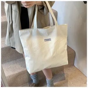Dettaglio della borsa tote in velluto a coste bianco crema indossata da una modella