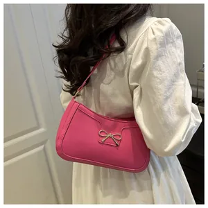 Détail du sac à bandoulière rose fuchsia avec boucle métallique à nœud doré