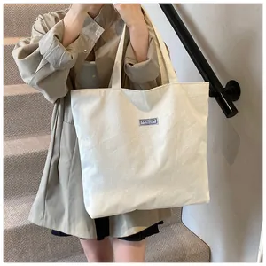 Dettaglio della borsa tote in velluto a coste bianco con etichetta blu sulla spalla