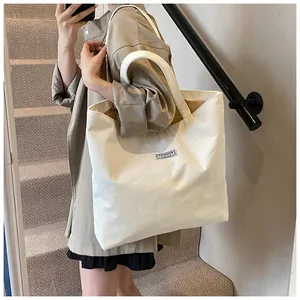 Dettaglio della borsa tote in velluto a coste bianco con etichetta indossata a spalla