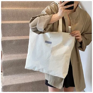 Dettaglio della borsa tote in velluto a coste bianco con etichetta blu e trama morbida