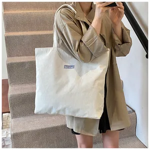 Dettaglio della borsa tote in velluto a coste beige con etichetta FASHION sul davanti