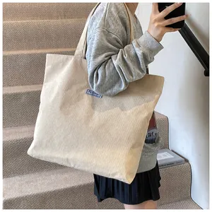 Dettaglio della borsa tote in velluto a coste beige con trama a righe ed etichetta