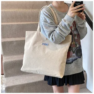 Dettaglio della borsa tote in velluto a coste bianco crema con etichetta blu