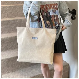 Vista dettagliata della borsa tote grande in velluto a coste bianco crema con etichetta