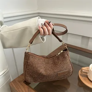 Chic brown woven shoulder bag with gold hardware and fashion label shown in hand