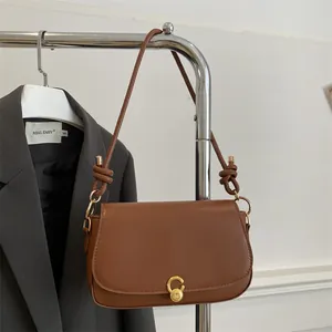 Brown leather saddle bag with gold metal clasp and elegant knot strap detail
