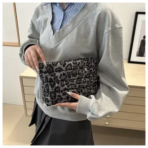 Close-up of leopard print quilted clutch bag held by model in a minimalist setting