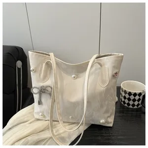 Detail of off-white tote bag featuring faux pearls, metal bows and pink heart gems
