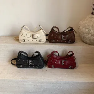 Sacs portés épaule à rivets en crème, marron, noir et rouge sur des marches en marbre