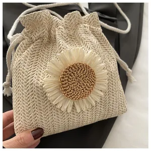 Dettaglio borsa a secchiello in paglia beige con fiore 3D bianco per l'estate mare