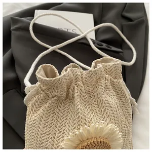 Dettaglio della borsa a secchiello in paglia beige con un grande girasole decorativo