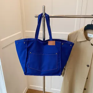 Borsa tote in tela blu reale con cuciture a contrasto e dettagli in pelle su supporto